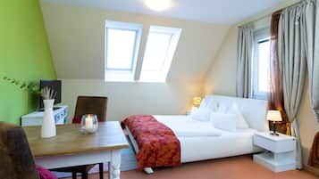 Un dormitorio con cama, mesita de noche, lámpara y un pequeño escritorio con planta y jarrón.