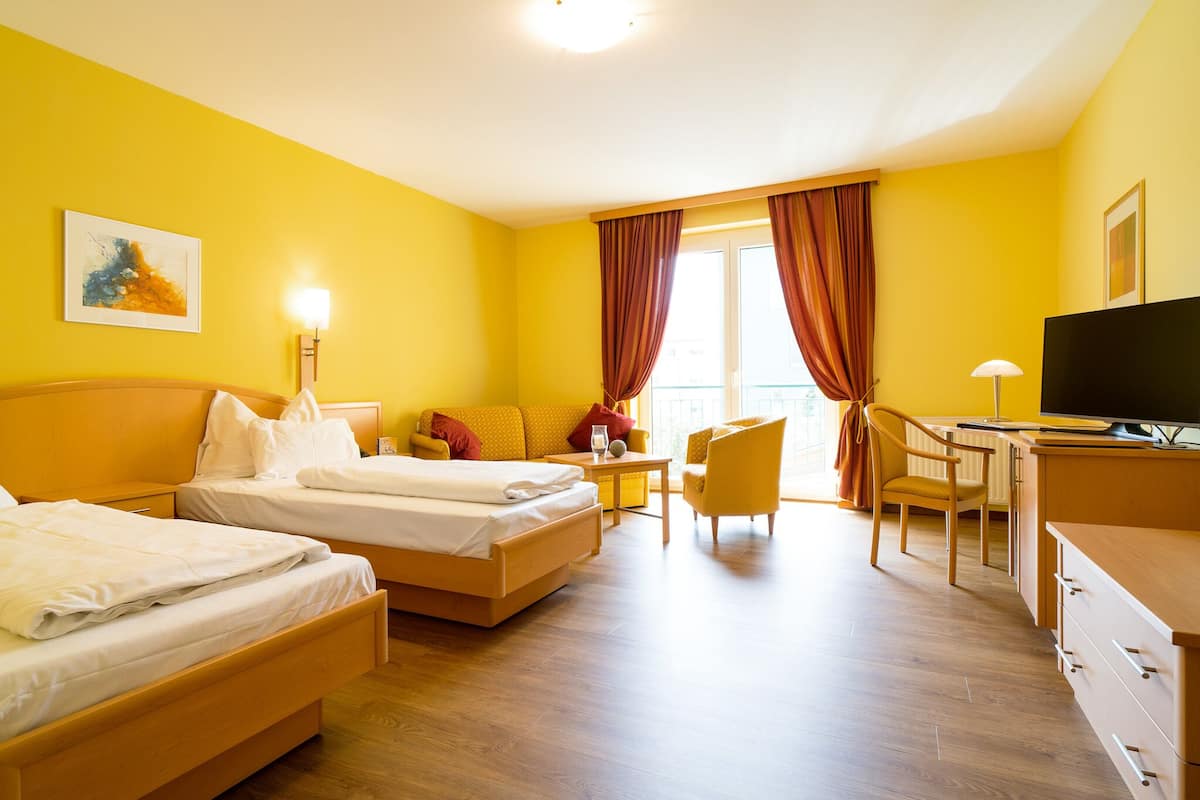 A hotel room with two beds, a desk, a chair, and a television.
