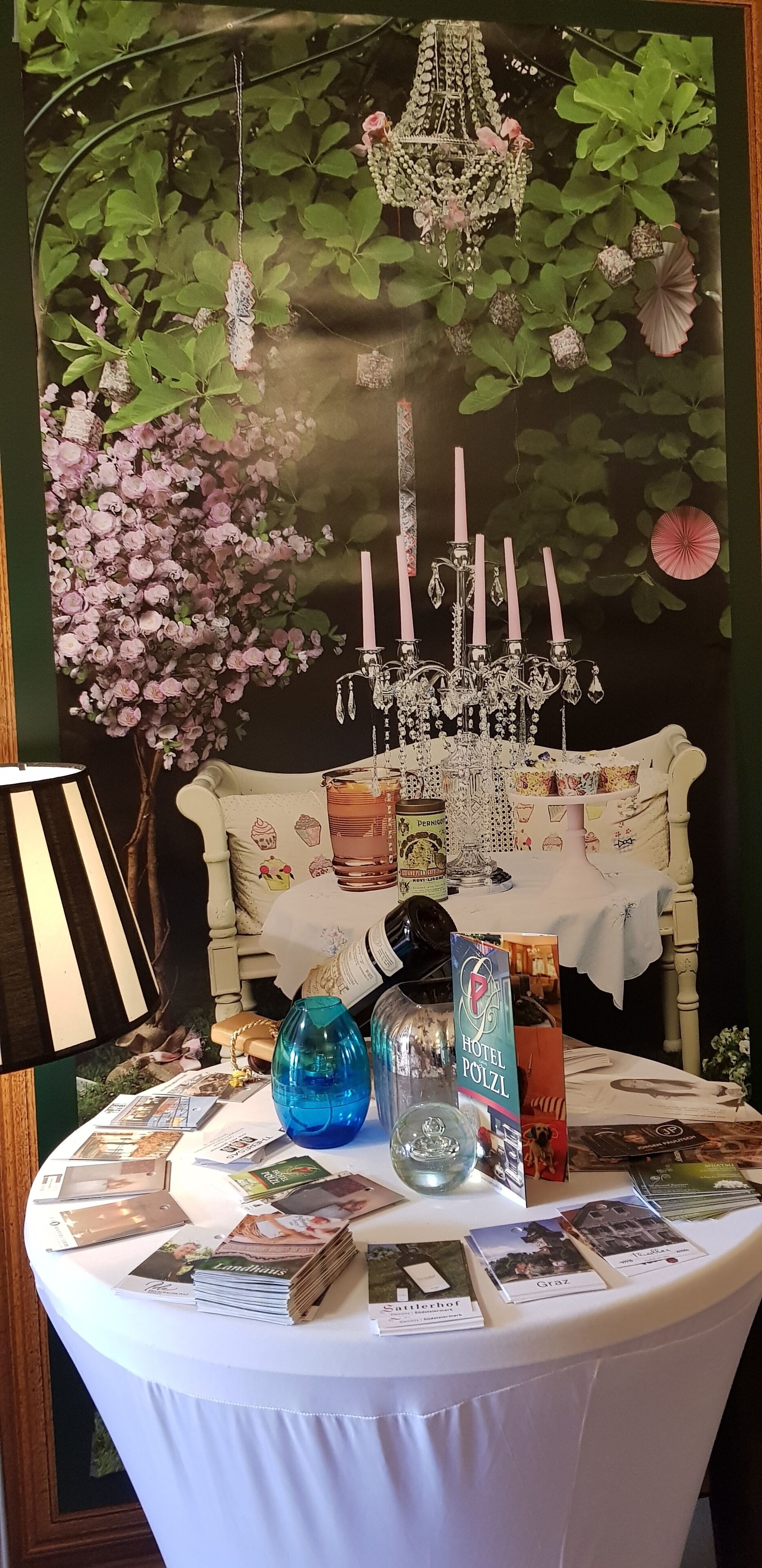 Uma mesa com folhetos, um candelabro e um painel decorativo.