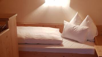 Un dormitorio acogedor en el ático, con techo inclinado, paredes de madera y una cama individual con almohadas.