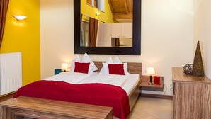 Habitación de hotel con cama, mesitas de noche y un espejo, y una decoración en tonos rojo y blanco.