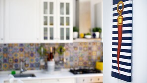 Una cocina con armarios blancos, salpicadero de azulejos y una estufa.