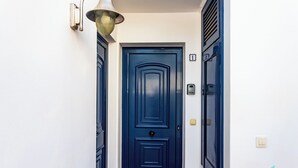 Une porte bleue dotée d’une poignée moderne et d’un luminaire placé au-dessus.