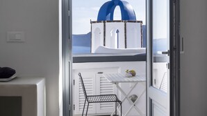 A view from a balcony with a white railing, a small table with a vase, and a chair. - Bluedome Cavehouses by Otium Villas (Santorini)