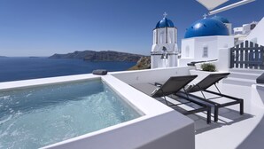 A rooftop infinity pool with lounge chairs, a white building with blue domes, and a view of the sea and distant land. - Bluedome Cavehouses by Otium Villas (Santorini)