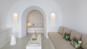Ein schlicht eingerichtetes Wohnzimmer mit einer Couch, einem Couchtisch und einer Vase mit einer Blume.