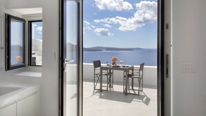 Ein Balkon mit Tisch für zwei Personen, mit Blick auf eine malerische Seelandschaft und Inseln.