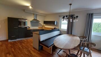 A modern kitchen with dark cabinetry, a built-in oven, and a central island with seating.