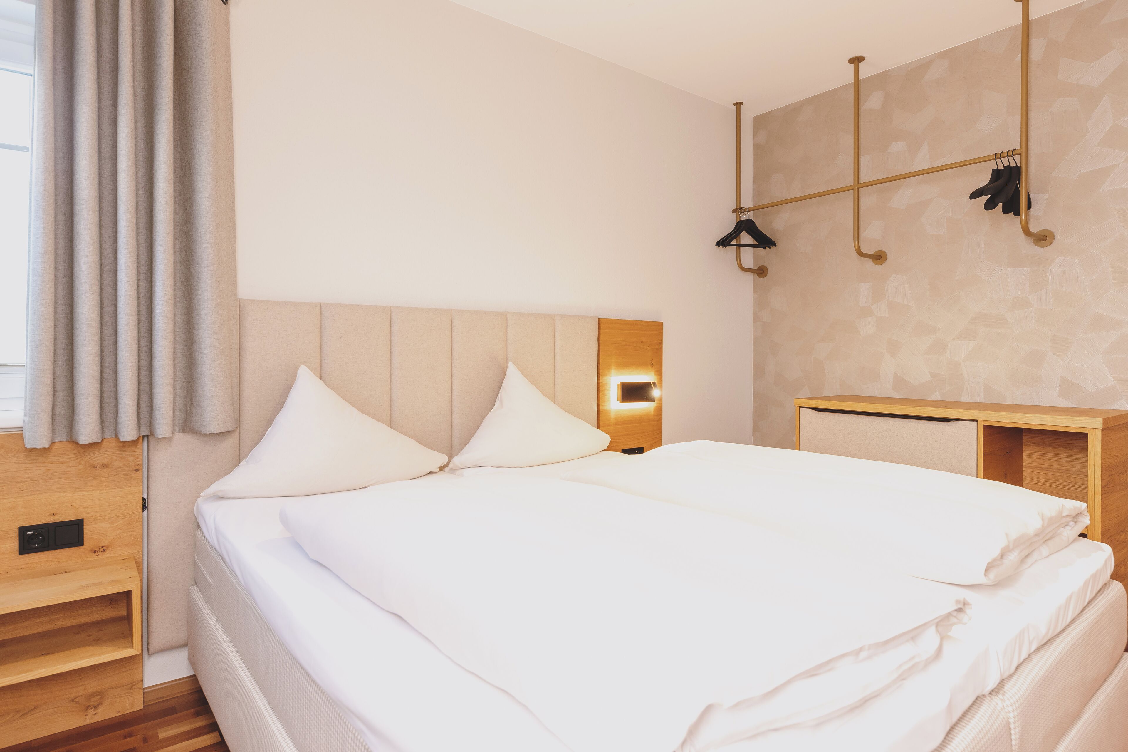 A neatly made bed with white linens, a wooden headboard, and a bedside table with a lamp.