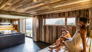 Un intérieur en bois comprenant un espace sauna, une table de massage et un bassin en pierre.