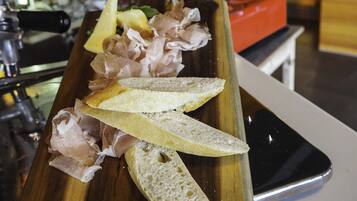 Una tabla de madera con pan en rodajas y embutidos sobre una mesa en un restaurante.