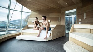 Une salle de spa moderne avec un plancher en bois, de grandes fenêtres et un banc en bois.