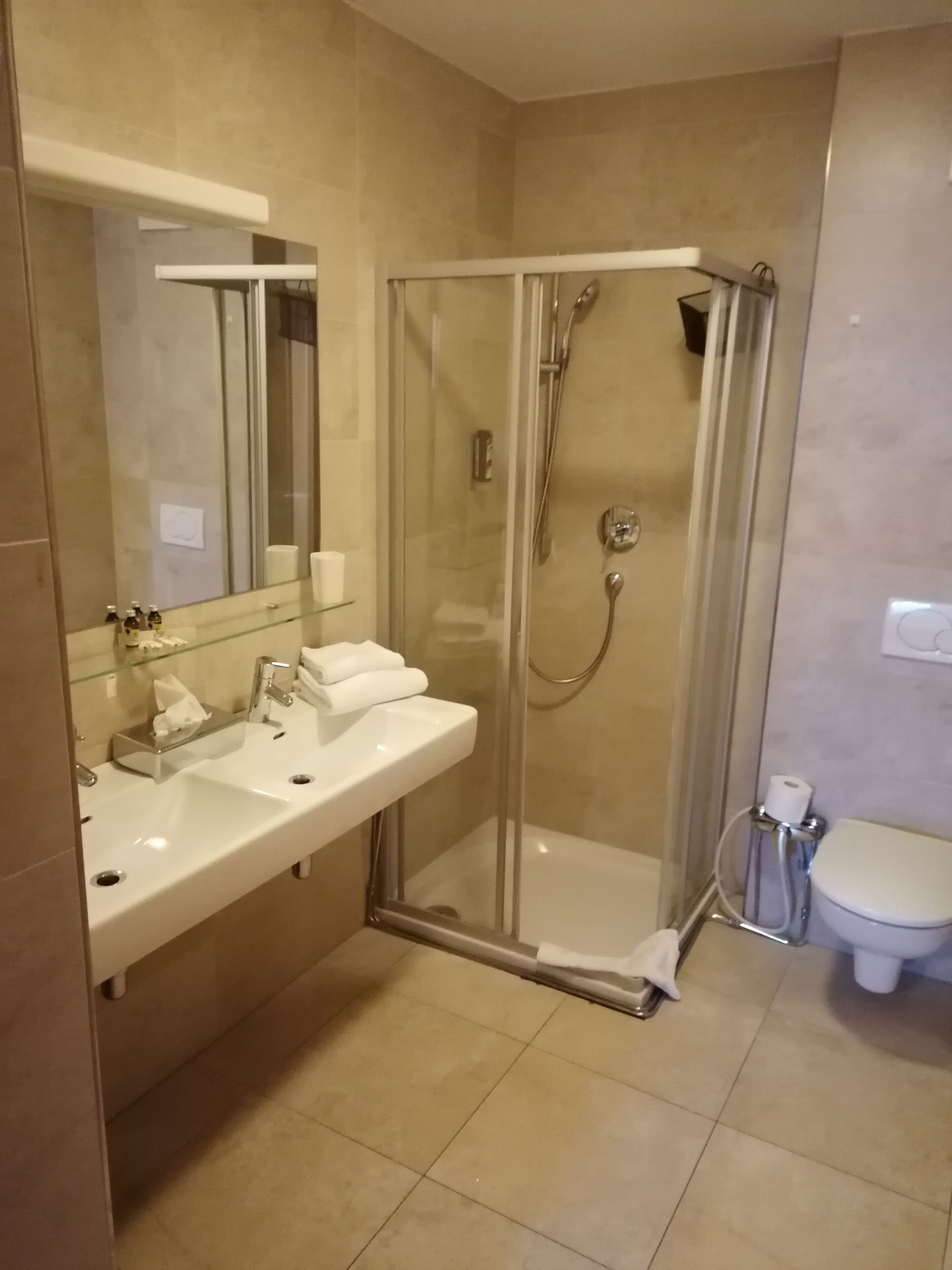 Un baño moderno con ducha de mampara de vidrio, lavamanos blanco con espejo y retrete.