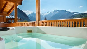 Un bain à remous avec une terrasse en bois et une vue sur les montagnes.