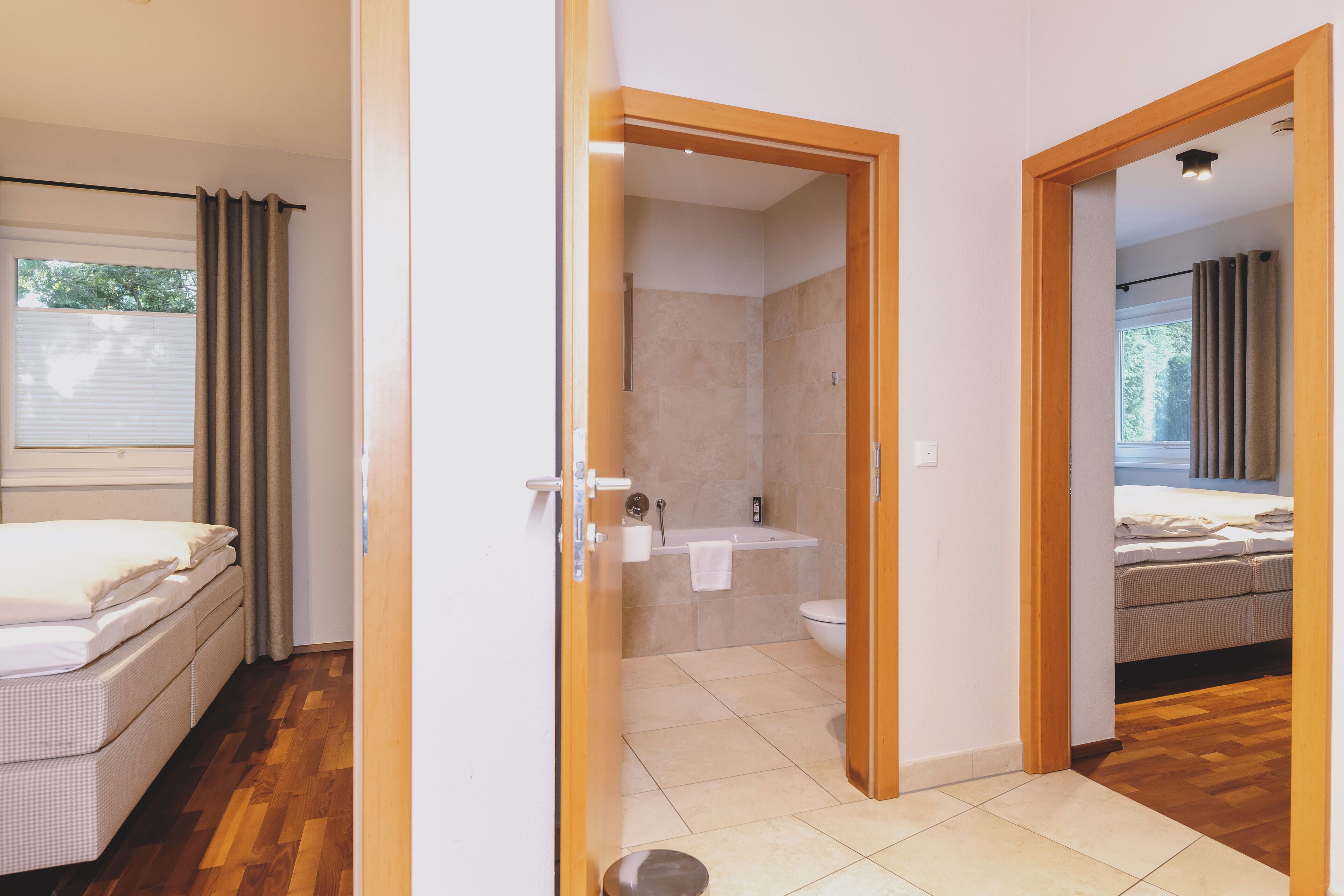 A hotel room with a bed, a bathroom with a bathtub and toilet, and a wooden floor.