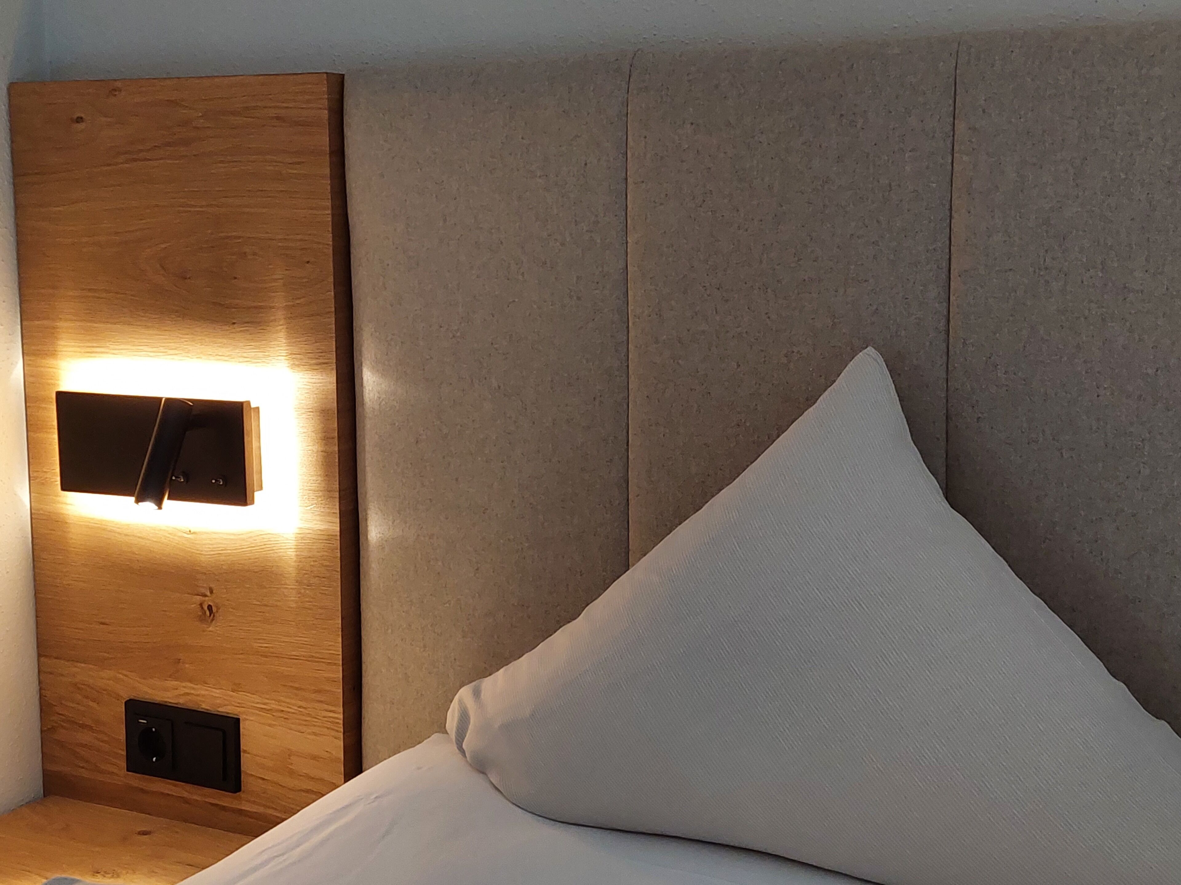 A bed with a wooden headboard and a light fixture.