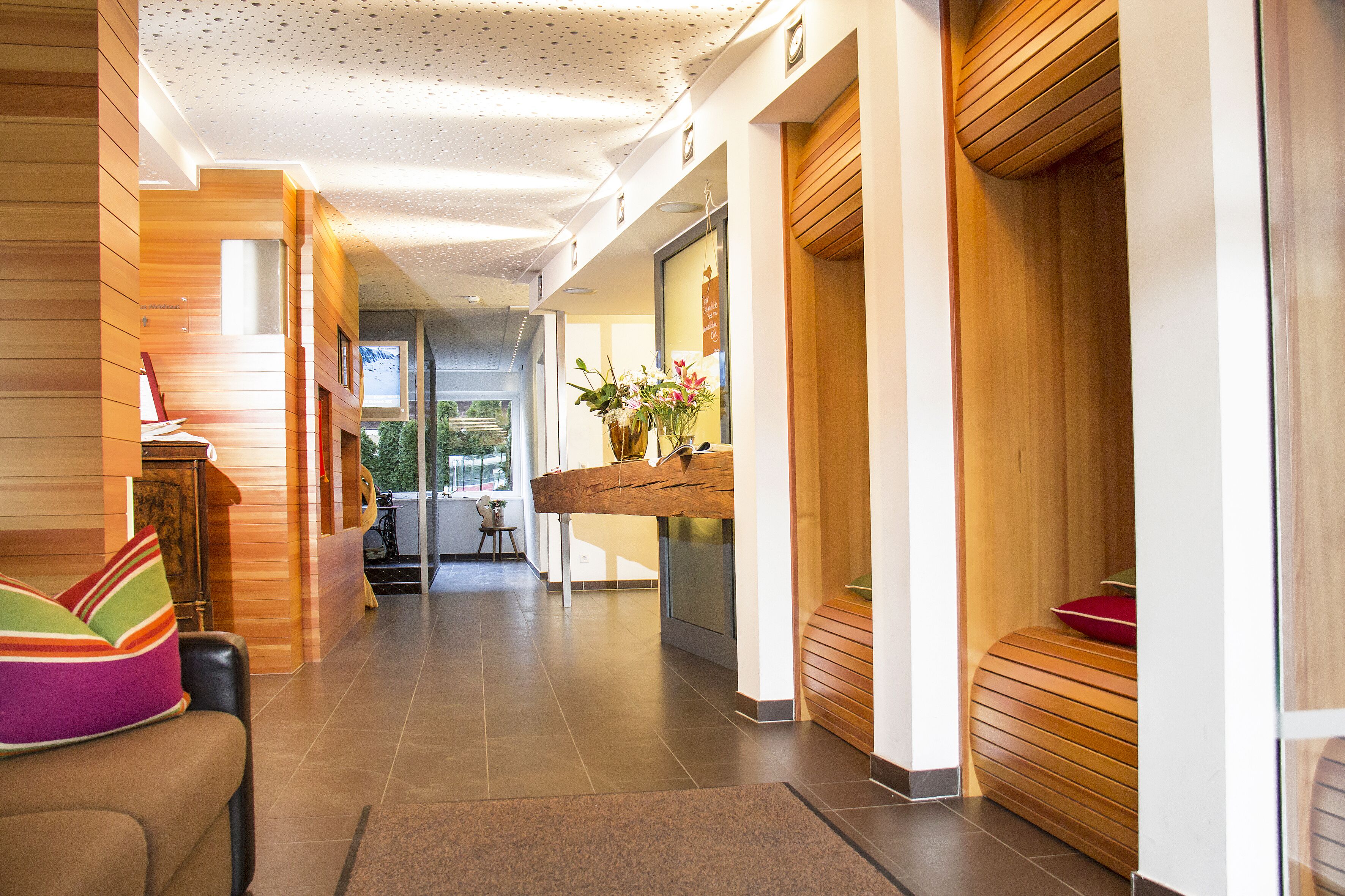 En moderne hotellobby med reception, siddeområde og trædetaljer.