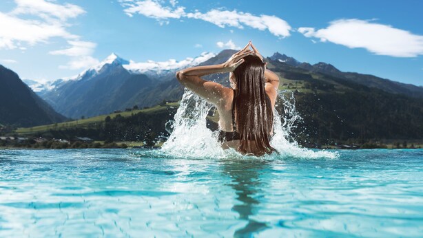 Une personne se trouve dans une étendue d’eau, avec des montagnes en arrière-plan.