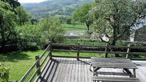 Eine Holzterrasse mit Blick auf eine grüne Landschaft und Hügel.