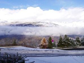 A snow-covered landscape with a mountain in the background and a road in the foreground.