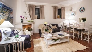 A living room with a fireplace, a dining table, and a sofa. - Farmhouse in Maremma a few steps from the sea (Albinia)
