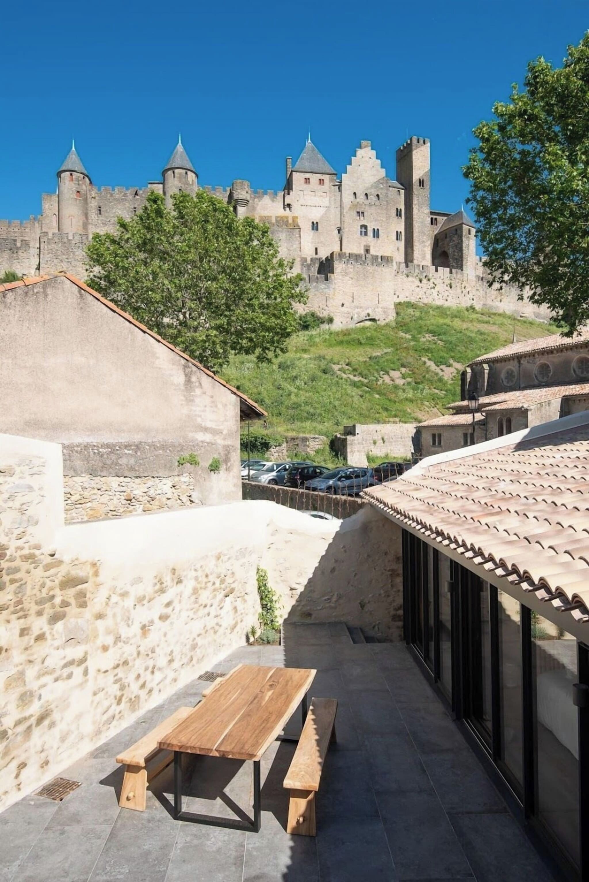 Un cortile con una panchina di legno e vista su un castello storico.