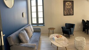 A living room with a sofa, a round table, a chair, a small round table, and a decorative item.