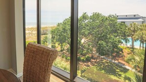 A room with a large window overlooking a landscaped area with trees and a pool.