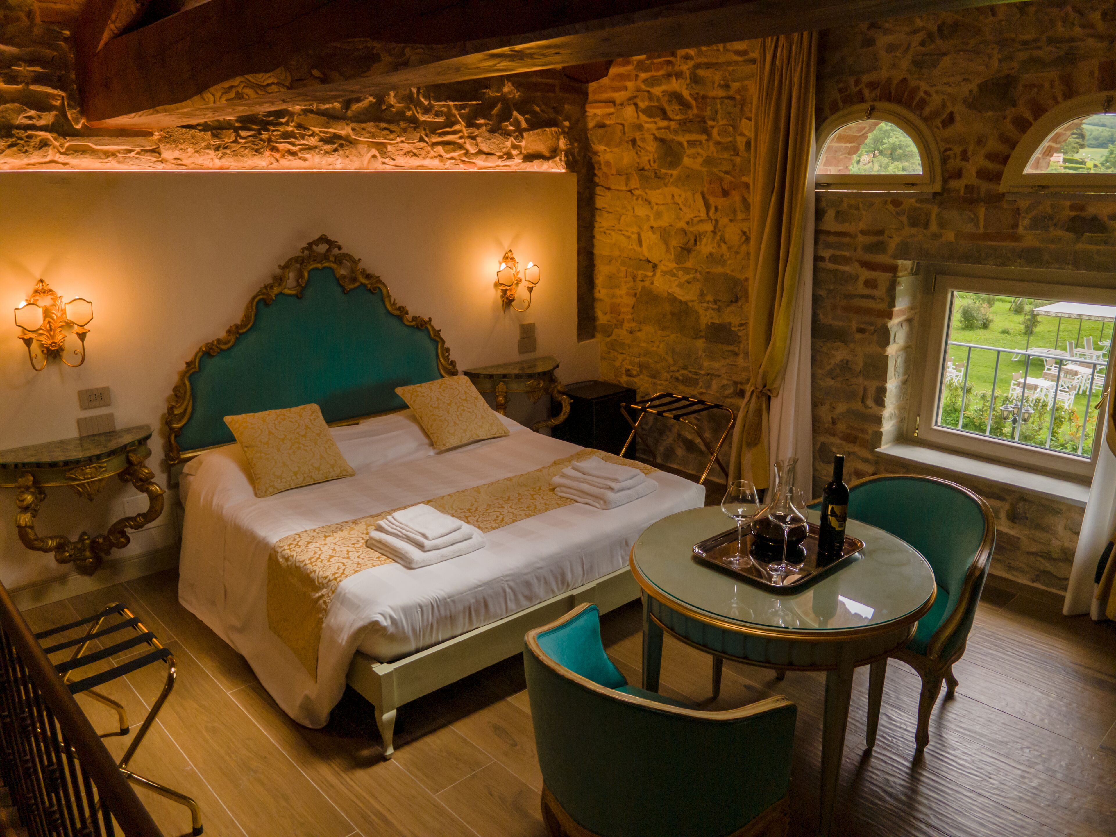 Una camera da letto elegante con un letto grande, due comodini, un tavolo rotondo con sedie e vista all'esterno tramite una finestra.