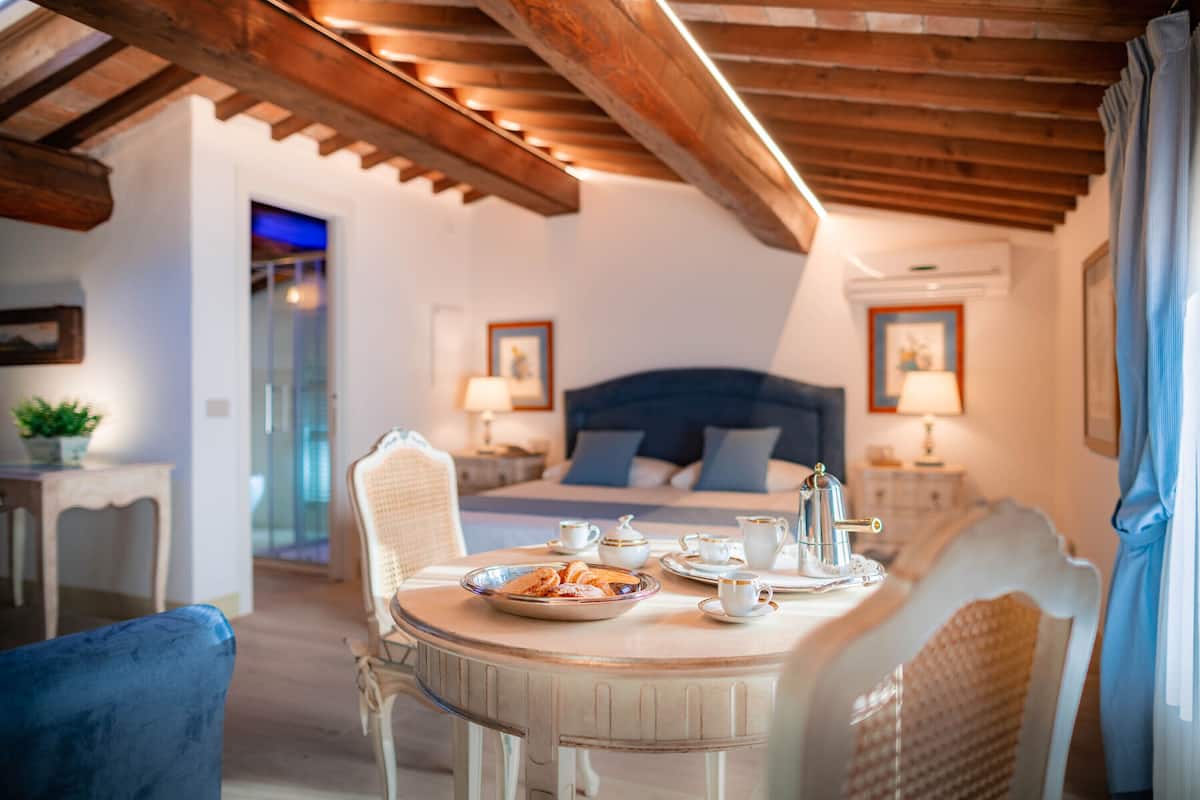 A bedroom with a bed, bedside tables, and a dining table with breakfast items.