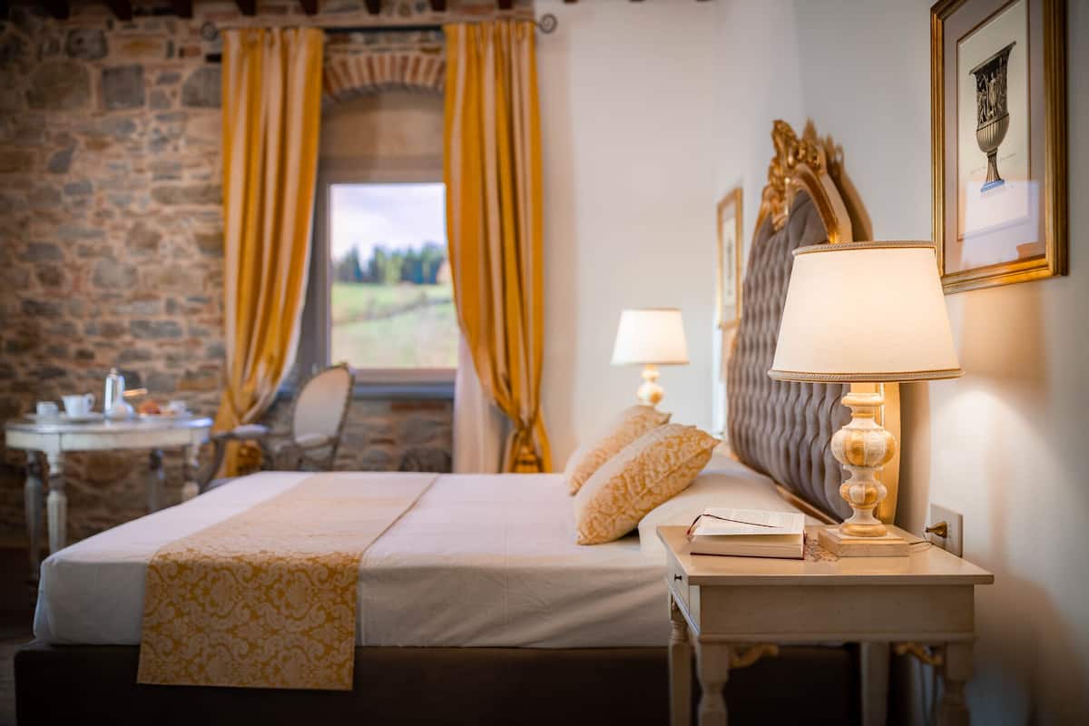 A neatly made bed with a patterned bedspread, a bedside lamp, and a chair.