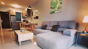 A modern living room with a grey sofa, a coffee table, and a dining area with wooden chairs. - Forest City Ataraxia Park 4  by Wastone (Gelang Patah)