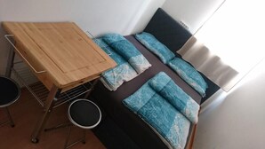 A small room with a bed, a wooden table, and a small stool. - ABAI Hostel (Vienna)