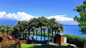 A pool area with a slide, surrounded by palm trees and a view of the sea.