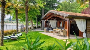 A cozy outdoor seating area with a table and chairs, surrounded by lush greenery and a view of a body of water.
