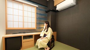 A room with tatami flooring, a low wooden desk, a sliding shoji screen, and a wall-mounted air conditioner.