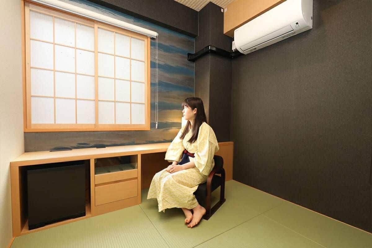 A room with tatami flooring, a low wooden desk, a sliding shoji screen, and a wall-mounted air conditioner.