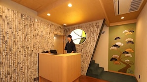 A reception desk with a modern design, a wall with a vertical pattern, and a mural of a tree with clouds.
