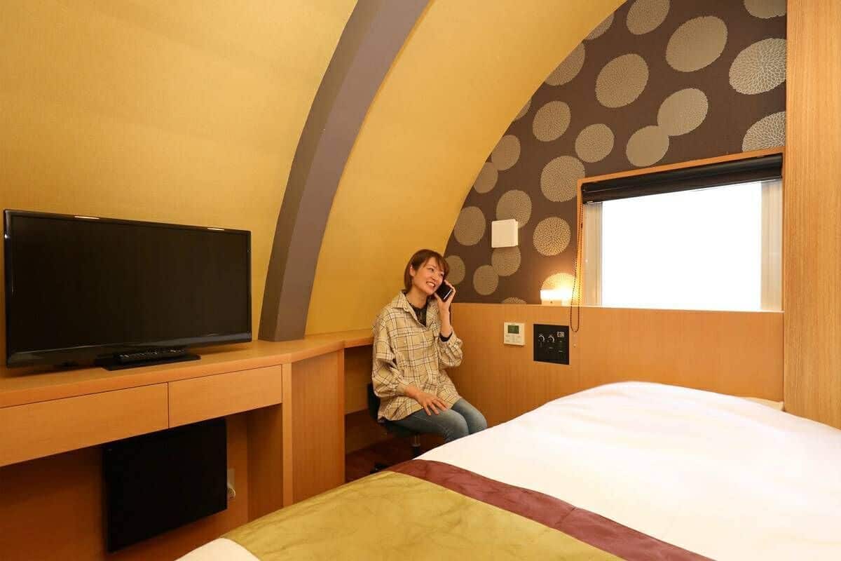 A room with a bed, a desk with a television, and a window with a view.