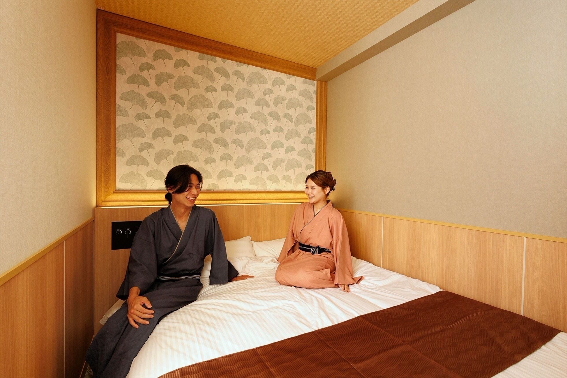 A hotel room with a bed, a wooden headboard, and a patterned wall.