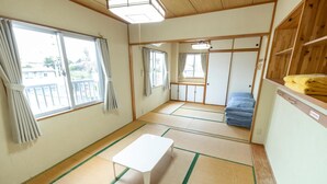 Een traditionele Japanse kamer met tatami vloerbedekking, een witte lage tafel en uitzicht door een schuifdeur.