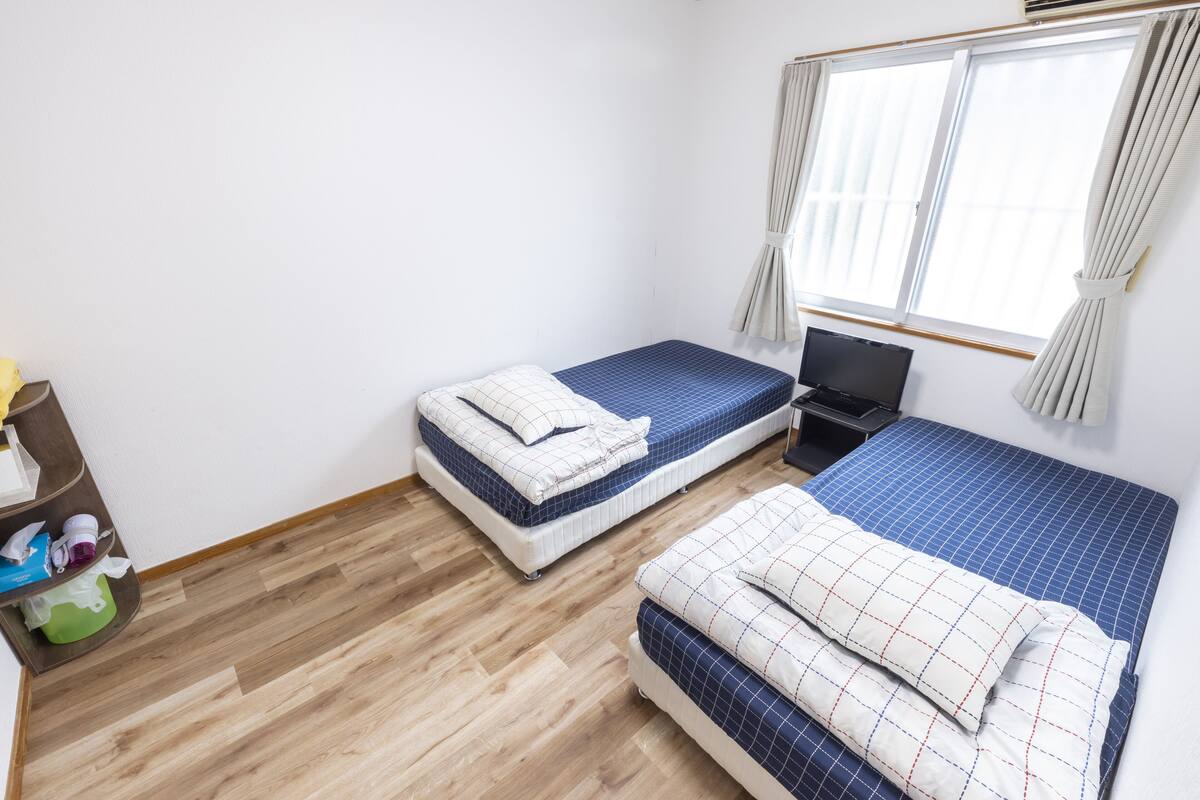 A room with two beds, a TV, and a window with curtains.