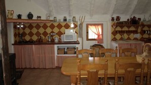 A cozy kitchen with a wooden table and chairs, a microwave, and various kitchen utensils. - Salvador's barrack (Canyadora)
