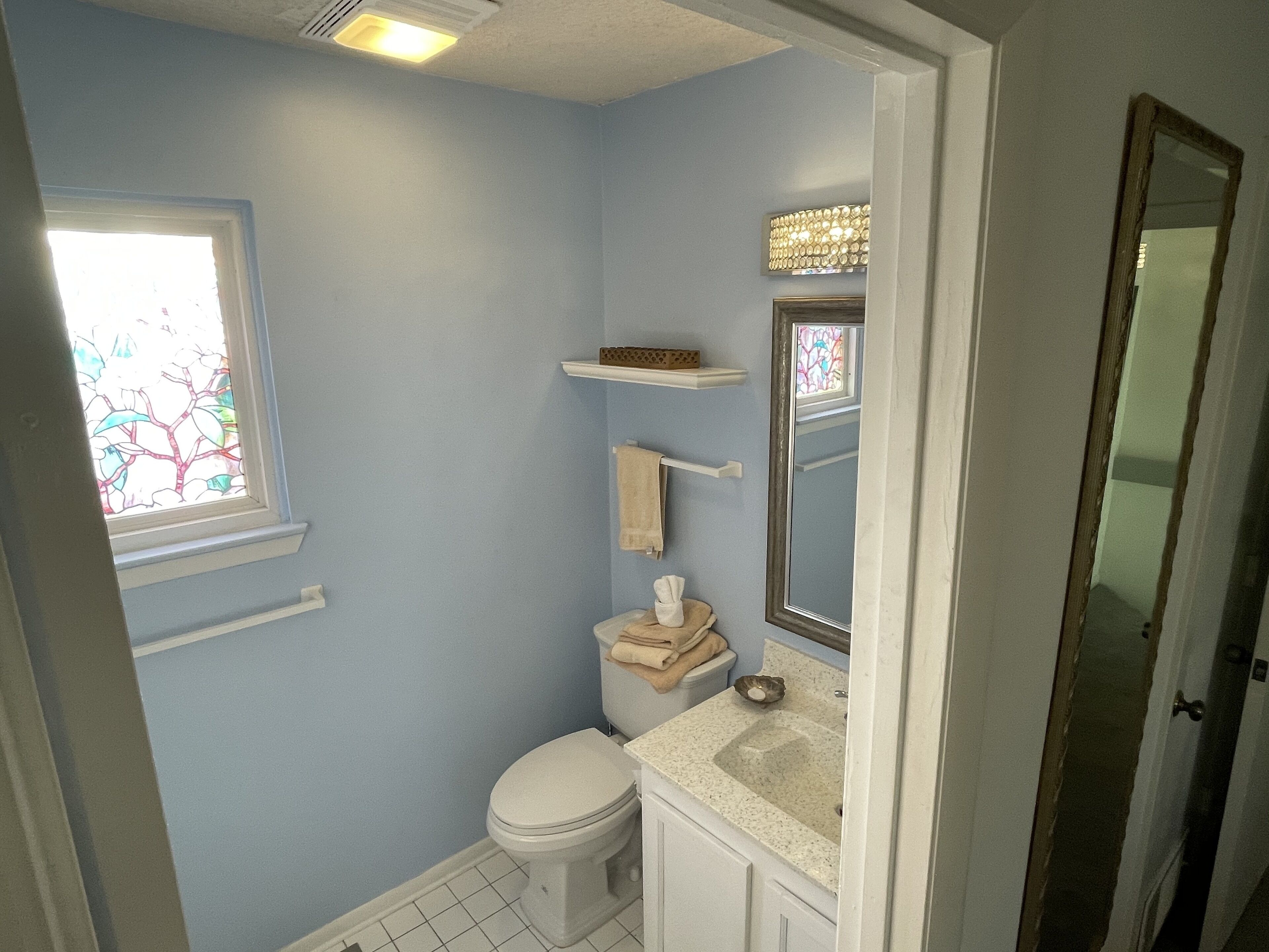 Une salle de bain équipée de toilettes, d’un lavabo et d’une fenêtre ornée de vitraux.