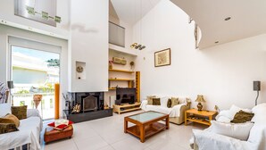 A modern living room with a fireplace, white sofas, a glass coffee table, and a TV. - Aeonian Mansion (Zakynthos)