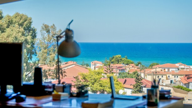 A view from a window overlooking a coastal town with red-roofed buildings and a clear blue sky. - Aeonian Mansion (Zakynthos)