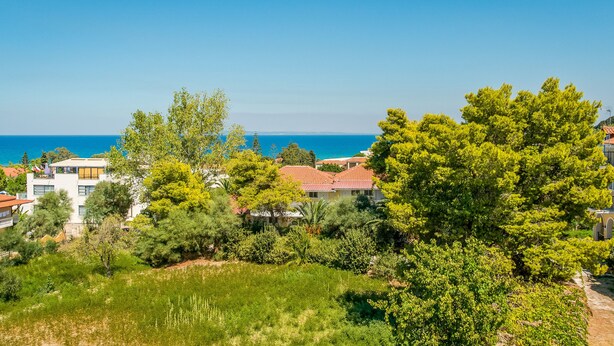 A coastal residential area with houses, greenery, and a view of the sea.