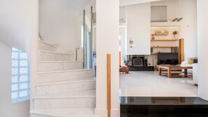A modern interior with a marble staircase, a flat-screen TV, and a minimalist living area. - Aeonian Mansion (Zakynthos)
