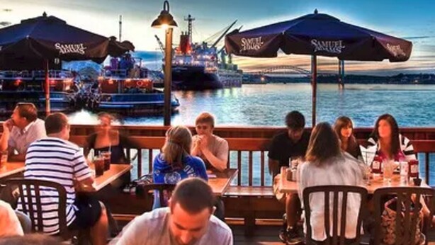 A waterfront restaurant with outdoor seating, umbrellas, and a view of a ship and bridge in the background. - Great Price;Beautiful, Spacious 3 Bed 2 Bath in a House Near Downtown Portsmouth (Portsmouth)