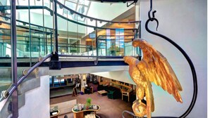 A modern interior with a large golden eagle sculpture, glass railings, and a seating area with tables and chairs. - Great Price;Beautiful, Spacious 3 Bed 2 Bath in a House Near Downtown Portsmouth (Portsmouth)